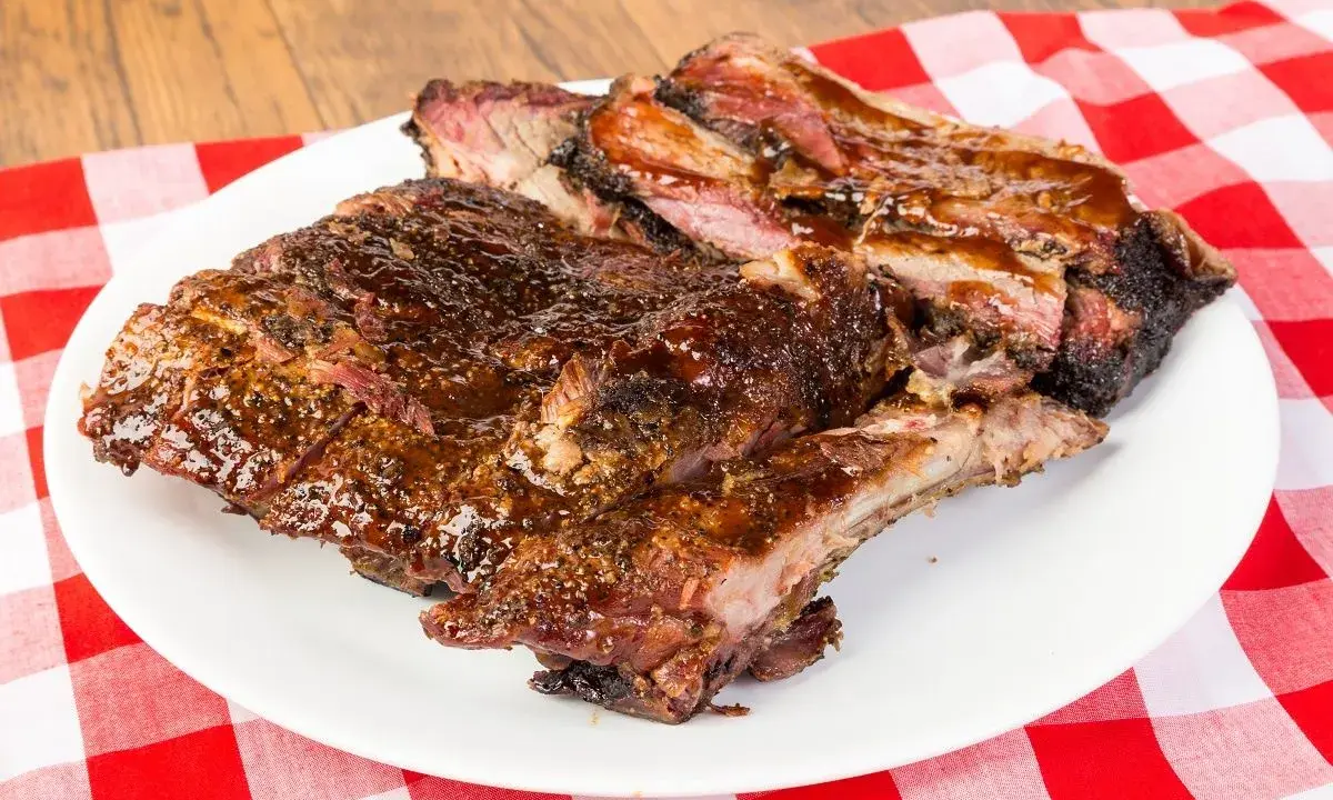 Soczyste, glazurowane żeberka BBQ na białym talerzu, idealne do jedzenia rękami. Pyszny sposób, jak jesc żeberka.