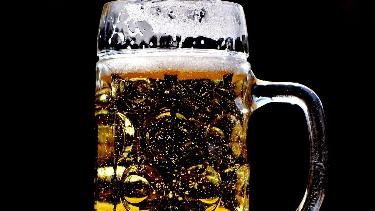 Złocisty lager w szklanej, tłoczonej kuflu, z obfitą pianką. Idealny rodzaj piwa na gorący dzień.