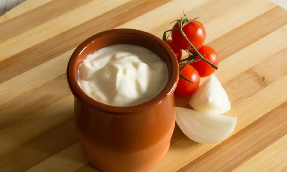 Gęsty jogurt w glinianym naczyniu, pomidorki koktajlowe i cebula. Jak zmniejszyć ostrość potrawy? Dodaj jogurtu!