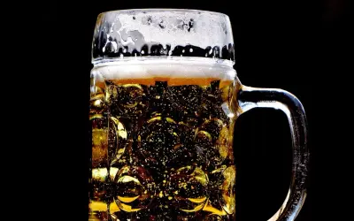 Złocisty lager w szklanej, tłoczonej kuflu, z obfitą pianką. Idealny rodzaj piwa na gorący dzień.