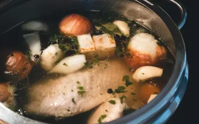 Szybkowar z bulionem: kawałki mięsa, cebula, czosnek, ziele angielskie i natka pietruszki tworzą aromatyczny rosół.