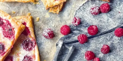 Pyszne ciasto francuskie z malinami, posypane cukrem pudrem. Idealne na letnie popołudnie.