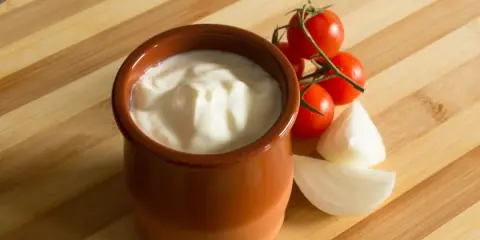 Gęsty jogurt w glinianym naczyniu, pomidorki koktajlowe i cebula. Jak zmniejszyć ostrość potrawy? Dodaj jogurtu!
