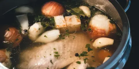 Szybkowar z bulionem: kawałki mięsa, cebula, czosnek, ziele angielskie i natka pietruszki tworzą aromatyczny rosół.