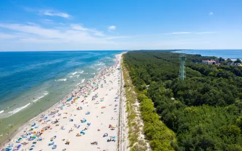 Słoneczna plaża pełna ludzi, las i wieża widokowa – to jedne z wielu **ciekawych miejsc na Pomorzu**.