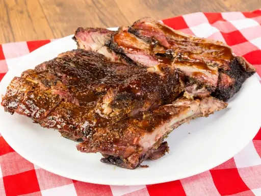 Soczyste, glazurowane żeberka BBQ na białym talerzu, idealne do jedzenia rękami. Pyszny sposób, jak jesc żeberka.