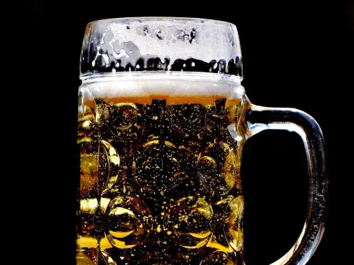 Złocisty lager w szklanej, tłoczonej kuflu, z obfitą pianką. Idealny rodzaj piwa na gorący dzień.
