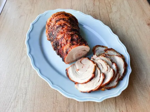 Soczysta rolada z boczku, pieczona do perfekcji, podana na błękitnej paterze. Idealna na rodzinny obiad.
