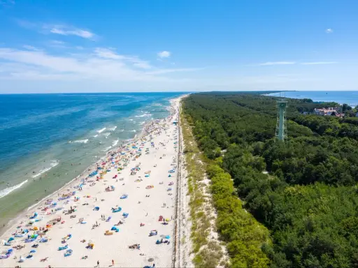 Słoneczna plaża pełna ludzi, las i wieża widokowa – to jedne z wielu **ciekawych miejsc na Pomorzu**.