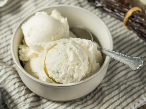 Pyszne, kremowe lody domowe w miseczce, obok laski wanilii. Idealne na upalne dni.