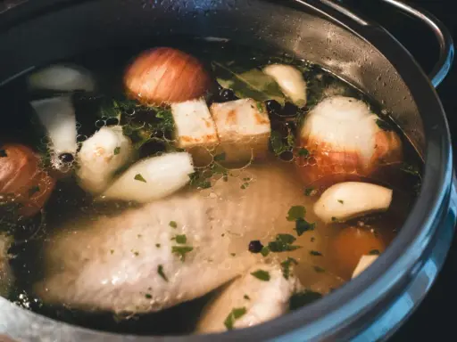Szybkowar z bulionem: kawałki mięsa, cebula, czosnek, ziele angielskie i natka pietruszki tworzą aromatyczny rosół.