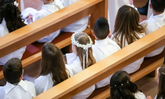 Dzieci w bieli, gotowe na Komunię Świętą. Wianek na głowie dziewczynki to piękne życzenia na komunie.