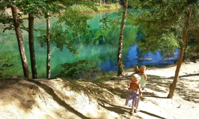 Dwie dziewczynki w słomkowych kapeluszach idą ścieżką nad turkusowe jezioro. Idealne miejsce, gdzie w góry z dziećmi latem.
