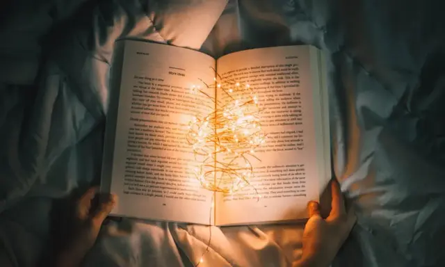 Książka z zapaloną girlandą światełek, idealna na życzenia dla nastolatka.
