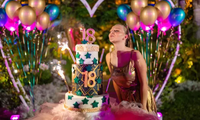 Dziewczyna zdmuchuje świeczki na tortcie z cyfrą 18, otoczona balonami i fajerwerkami. Idealne atrakcje na 18 urodziny!