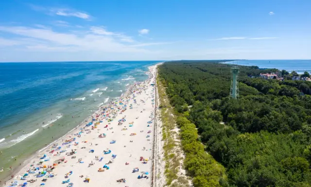 Słoneczna plaża pełna ludzi, las i wieża widokowa – to jedne z wielu **ciekawych miejsc na Pomorzu**.