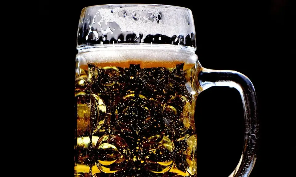 Złocisty lager w szklanej, tłoczonej kuflu, z obfitą pianką. Idealny rodzaj piwa na gorący dzień.