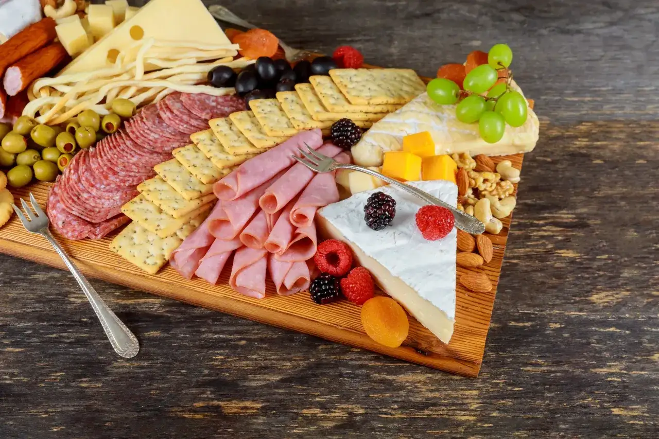 Inspiracja, jak udekorować talerz z wędlinami: ser, salami, szynka, oliwki, winogrona, orzechy i owoce tworzą apetyczną kompozycję.