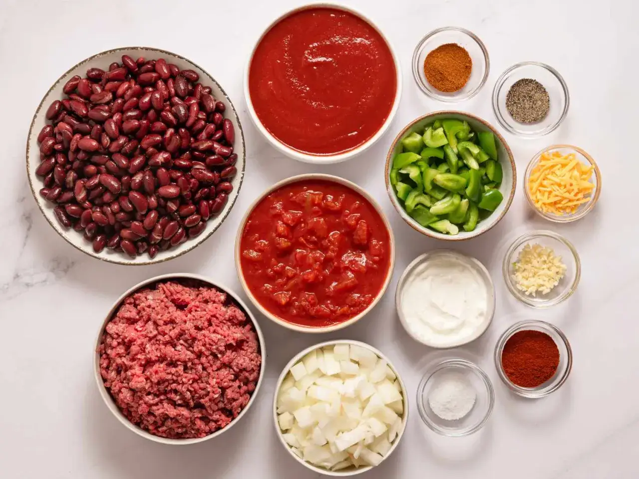 Składniki na chili: fasola, mielone mięso, pomidory, cebula, papryka, czosnek, przyprawy, ser. Jak zmniejszyć ostrość potrawy? Dodaj śmietanę lub jogurt.