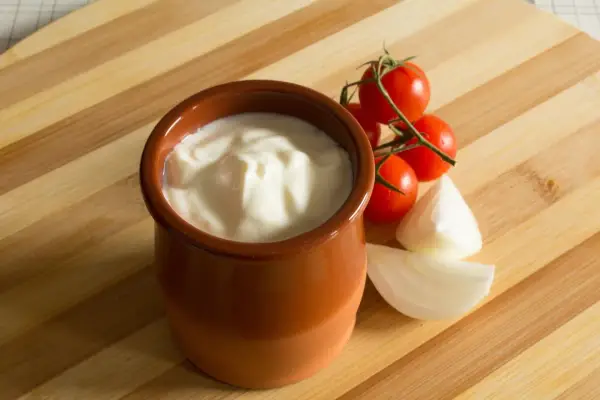 Gęsty jogurt w glinianym naczyniu, pomidorki koktajlowe i cebula. Jak zmniejszyć ostrość potrawy? Dodaj jogurtu!