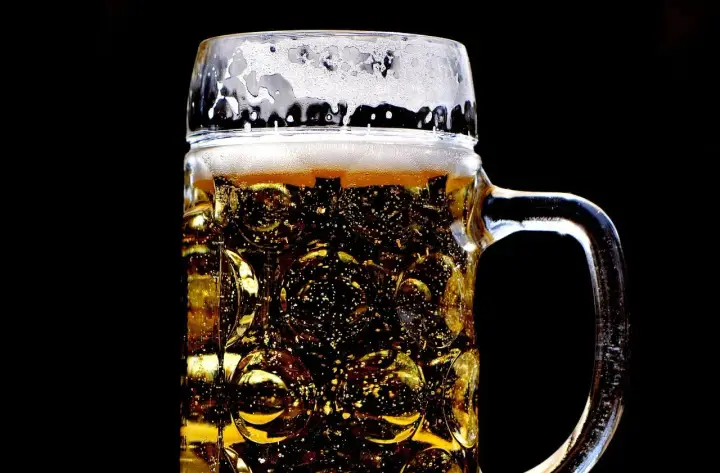 Złocisty lager w szklanej, tłoczonej kuflu, z obfitą pianką. Idealny rodzaj piwa na gorący dzień.