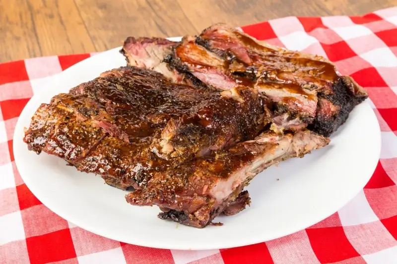 Soczyste, glazurowane żeberka BBQ na białym talerzu, idealne do jedzenia rękami. Pyszny sposób, jak jesc żeberka.
